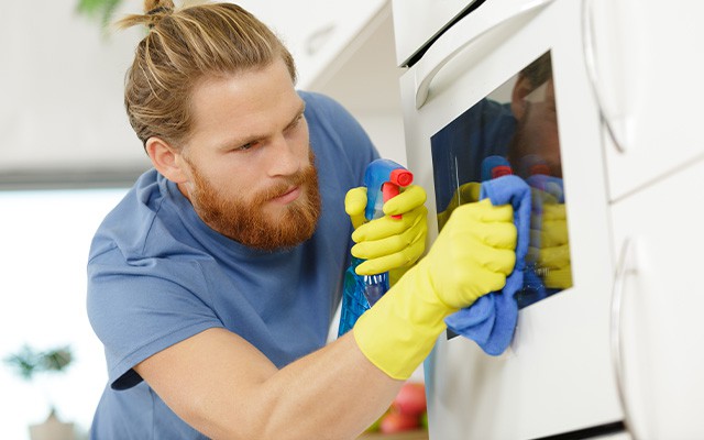 Mann mit Handschuhen putzt den Ofen