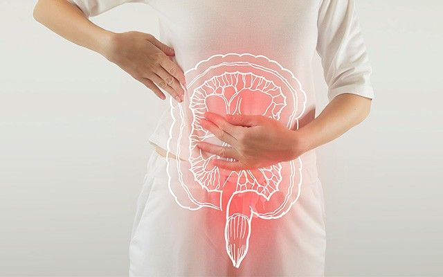Eine Person hält sich mit beiden Händen den Bauch, über dem die leuchtend weiße Silhouette eines menschlichen Dickdarms abgebildet ist.