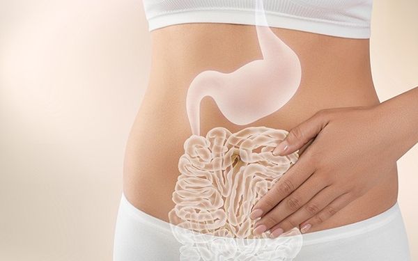 Eine Hand liegt flach auf einem nackten Bauch, auf dem eine leuchtend weiße Grafik von Magen und Darm eingeblendet ist.